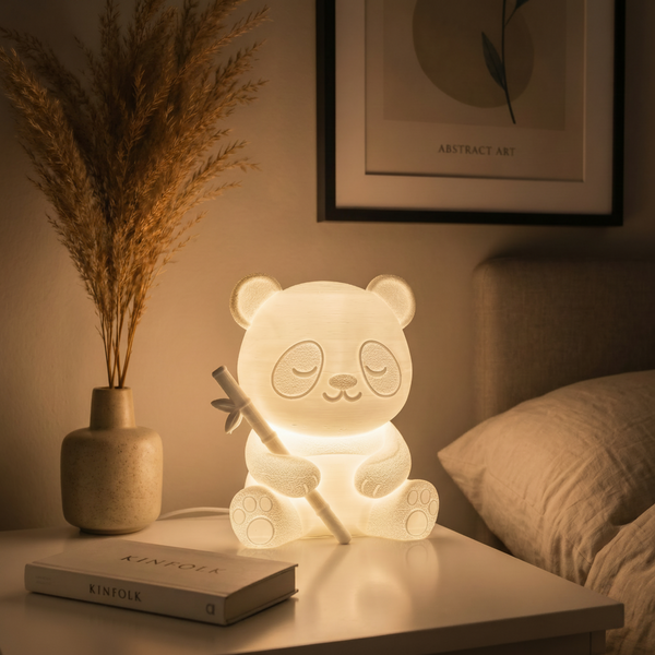 Panda-shaped night light on a bedside table with a book and decorative vase.