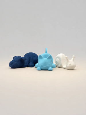 Three animal figurines in blue, white, and gray on a light gray background