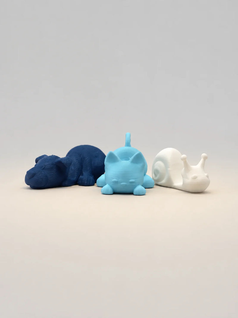 Three animal figurines in blue, white, and gray on a light gray background