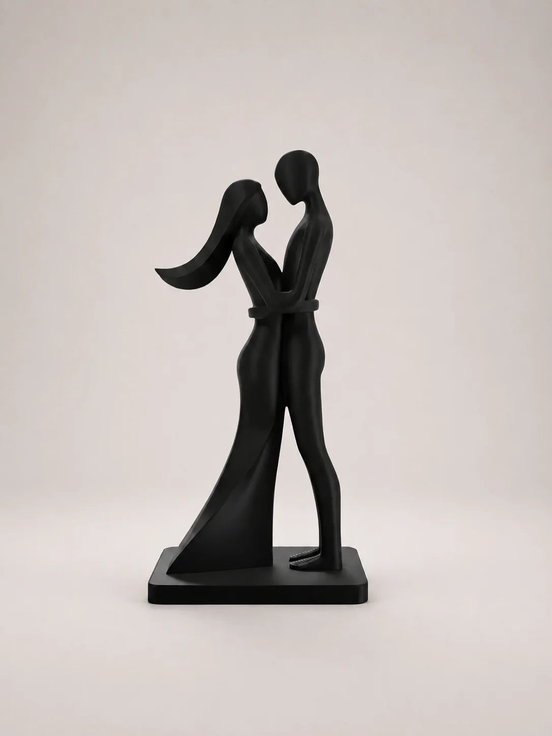 Black sculpture of two people embracing on a light gray background