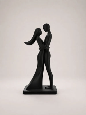 Black sculpture of two people embracing on a light gray background