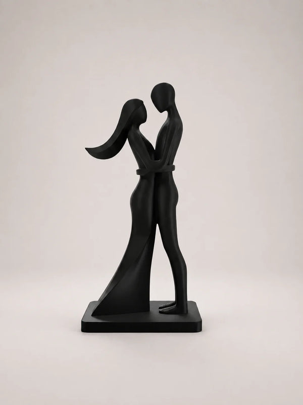 Black sculpture of two people embracing on a light gray background