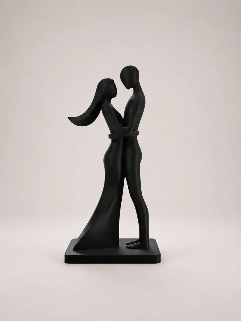 Black sculpture of two people embracing on a light gray background