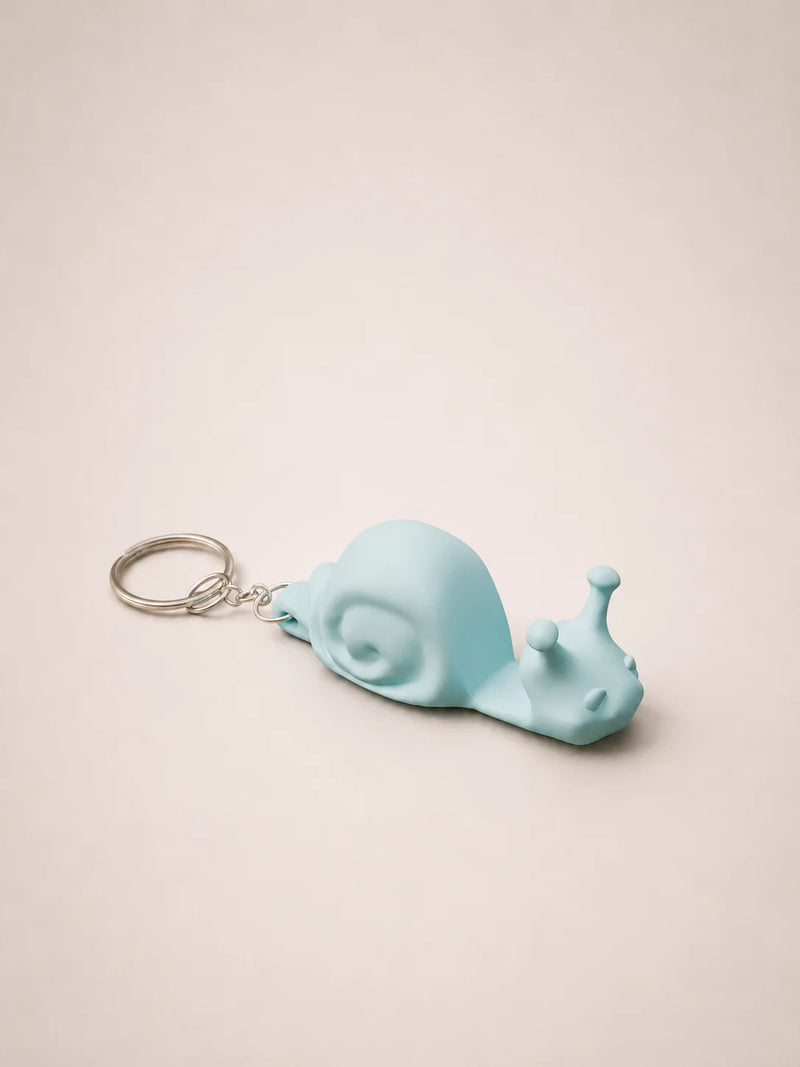 Light blue snail-shaped keychain on a beige background